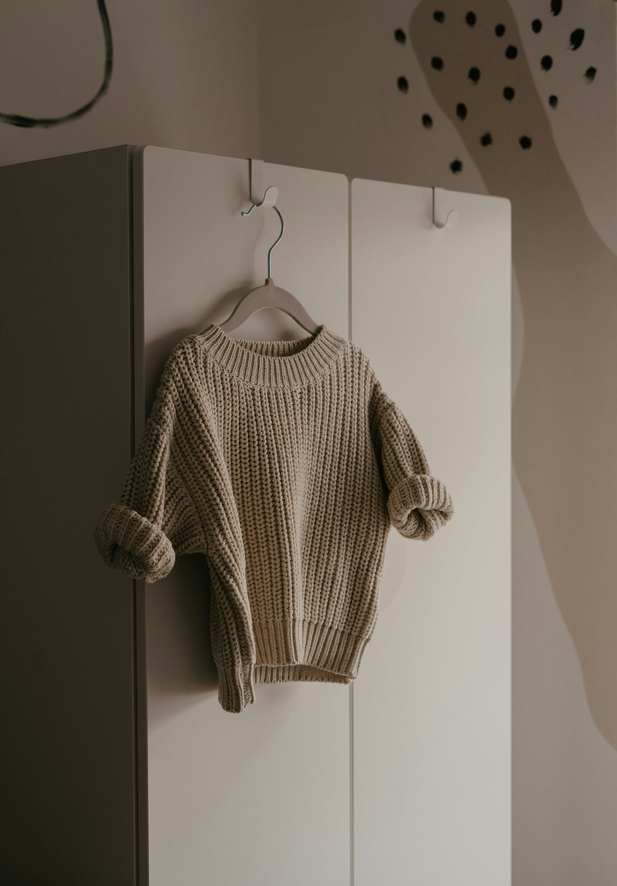 Knit sweater hanging on a hook in a bright room