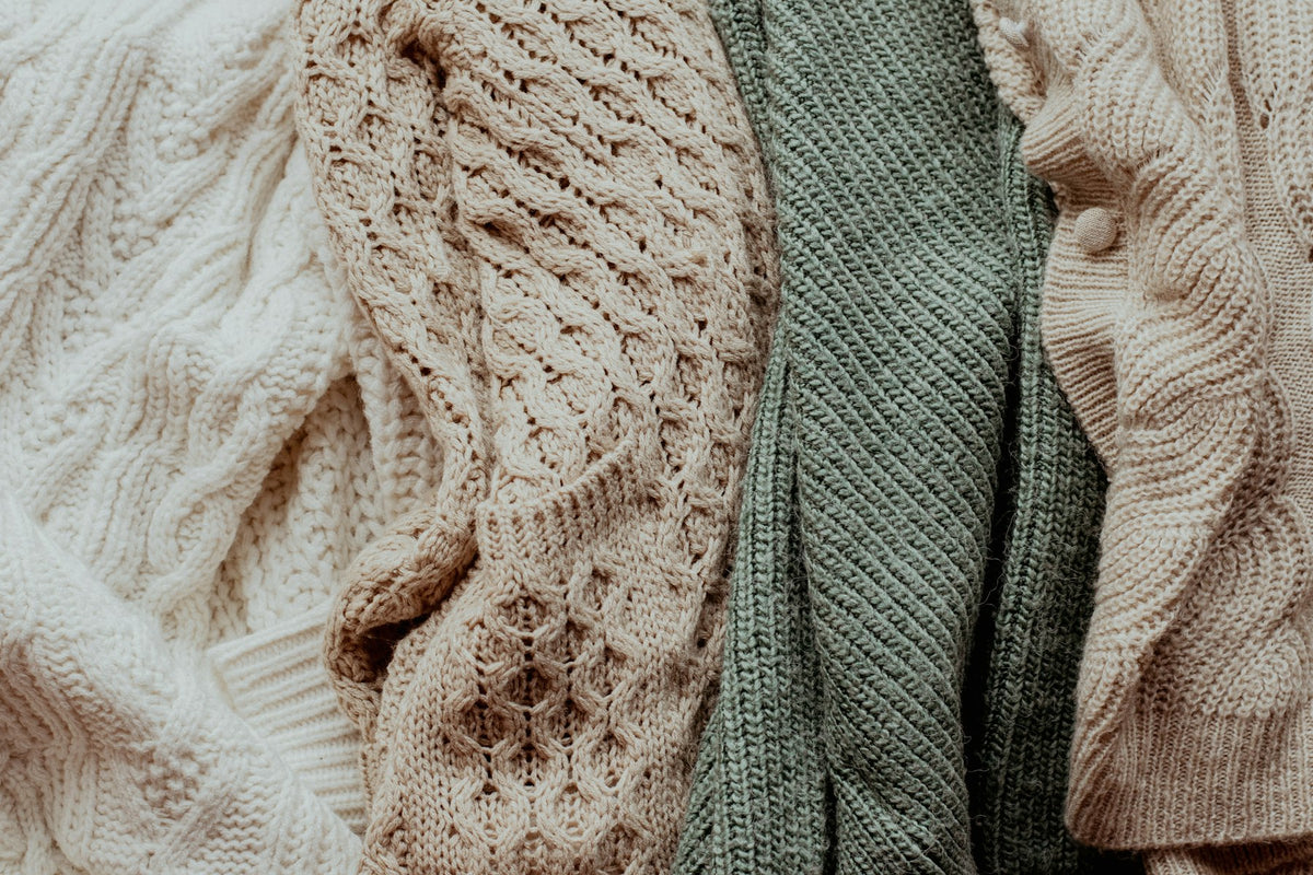 Pile of folded sweaters in neutral tones